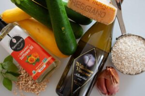 bottle of albarino laying on a kitchen counter with a selection of zucchini, shallot, parmesan cheese,rice and cooking oil