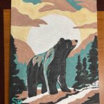 Graphic image of black bear on mountain saddle with the sunrise behind it